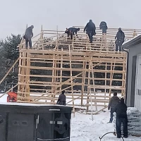 Workers construct a pole barn in winter.