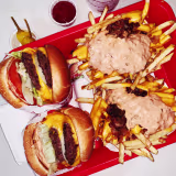 Double cheeseburgers and cheese fries on a tray in fast food restaurant