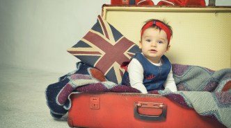 Cute Baby girl sitting in old vintage suitcase with British flag throw pillow